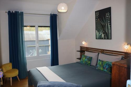 1 dormitorio con 1 cama con cortinas azules y ventana en L'autre Monde en Faverolles