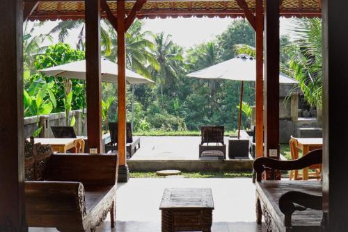 a patio with tables and chairs and umbrellas at The Banana’s Kumbe Villa in Tampaksiring