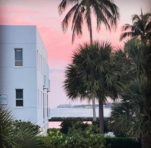 a white building with palm trees in front of the ocean at Fernando Flats in Palm Beach Shores