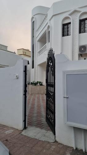 a white building with a black gate in front of it at البيت الابيض in Mawāliḩ