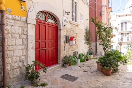 a red door on a building with potted plants at [Centro Storico] Redmood House a 5 min dal mare, Wi-Fi, A/C e Netflix in Barletta