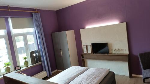 1 dormitorio con paredes moradas, 1 cama y espejo en zur Friedrichsruh en Oelsnitz/Vogtland