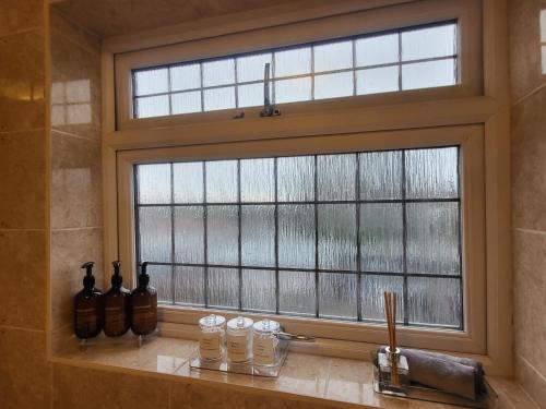 a window in a bathroom with bottles on a counter at Spacious Newly Renovated Three Bedroom House with private parking in Rainham