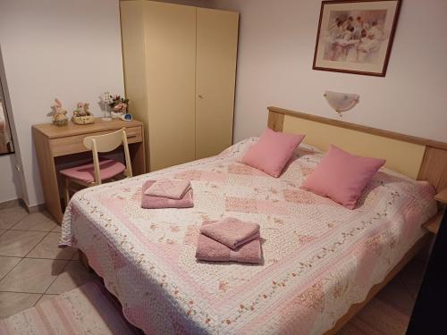 a bedroom with a bed with pink pillows on it at Apartment in green and quite area, close to beach in Šilo