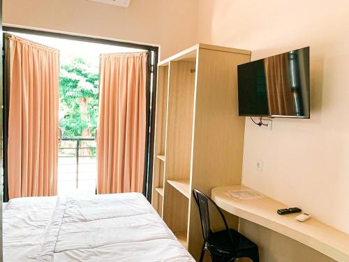 a room with a bed and a television on a wall at Kartiko Palagan Eksklusif Yogyakarta in Kejayan