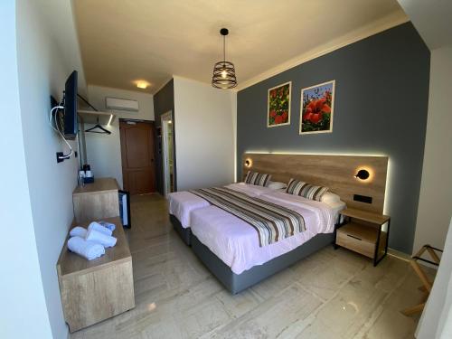 um quarto com uma cama e uma televisão de ecrã plano em Horizon Beach Hotel em Plakiás