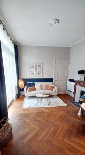 L'Elégant في لو بوتي كوفييِّ: غرفة معيشة مع أريكة بيضاء وأرضية خشبية