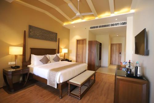 a bedroom with a large bed and a television at Essentia Luxury Resort & Spa Udaipur in Udaipur