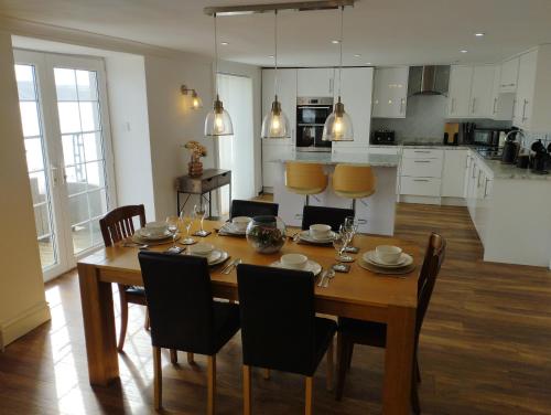 a kitchen and dining room with a wooden table and chairs at Waterfront Location, Balcony, Sea Views, Free Parking in Pembrokeshire