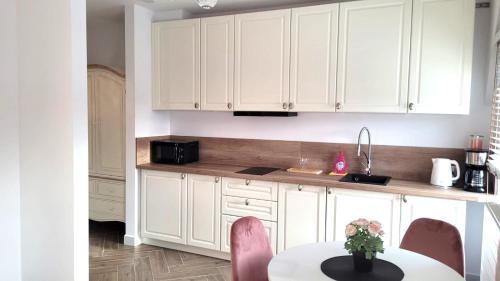 a kitchen with white cabinets and a table with flowers on it at APARTAMENT JARACZA 28/16 in Słupsk
