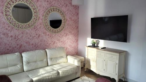 a living room with a couch and two mirrors at APARTAMENT JARACZA 28/16 in Słupsk