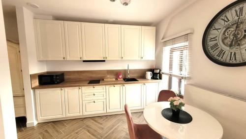 a kitchen with a table and a clock on the wall at APARTAMENT JARACZA 28/16 in Słupsk