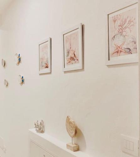 a white room with three pictures on the wall at Casa Gió Grazioso Appartamento a Porto Cervo in Liscia di Vacca