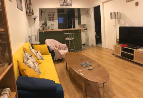 sala de estar con sofá amarillo y mesa en Maisonnette en ville, en Montargis