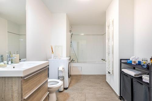 a white bathroom with a sink and a toilet at GuestReady - Bright getaway near la Défense in Nanterre