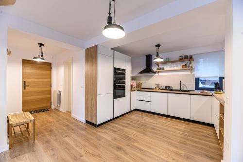 a kitchen with white cabinets and a wooden floor at Doftana Lake House in Teşila