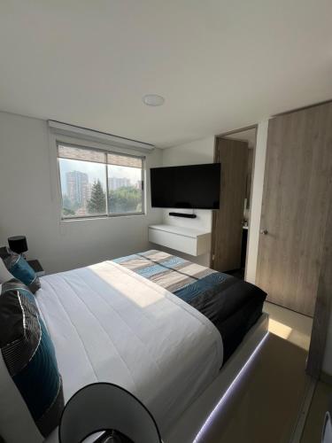 a bedroom with a large bed and a flat screen tv at Luxor apartamentos in Medellín