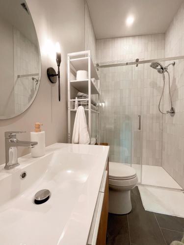 a white bathroom with a sink and a toilet at Elora’s Irvine River Suite in Elora