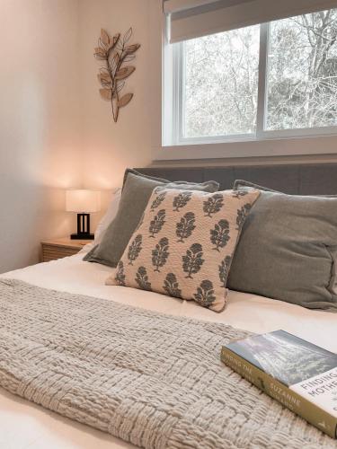 a bedroom with a bed with a book and a window at Elora’s Irvine River Suite in Elora