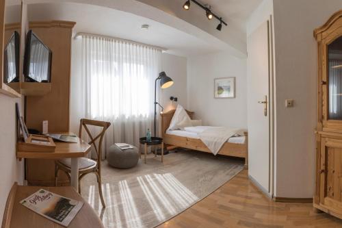 a bedroom with a bed and a desk and a table at Widmann's Löwen in Königsbronn
