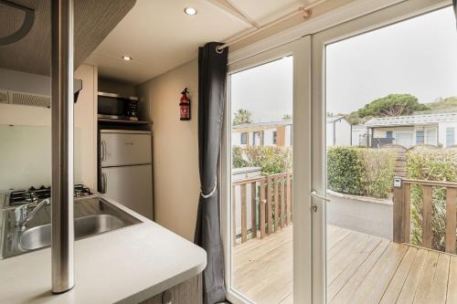 een keuken met een glazen schuifdeur naar een balkon bij Ohana Cottage in Fréjus