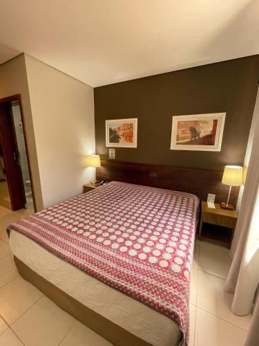 a bedroom with a bed with a red and white blanket at Taj Hotel in Três Lagoas