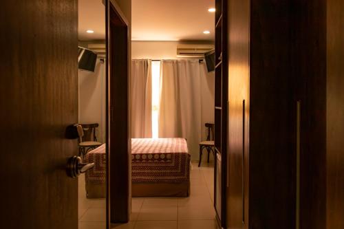 a door to a room with a bed and a window at Taj Hotel in Três Lagoas