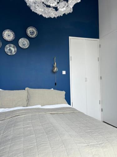 a blue bedroom with a bed and plates on the wall at Lovely small apartment in 'De Pijp' in Amsterdam