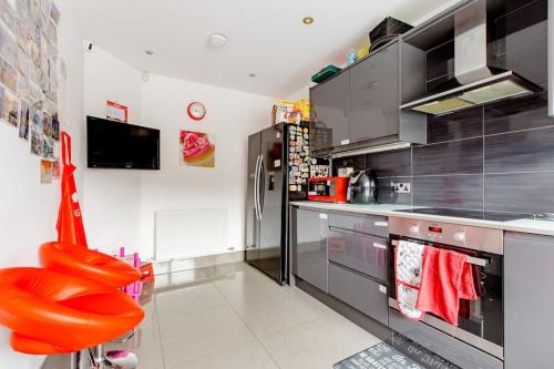 a kitchen with a refrigerator and a red seat at Lovely Comfy Double Bedroom with secure parking in Bexleyheath