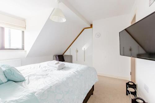 a white bedroom with a bed and a flat screen tv at Lovely Comfy Double Bedroom with secure parking in Bexleyheath