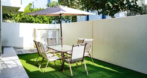 a table and chairs with an umbrella on the grass at Luxury Villa by the sea in Fujairah