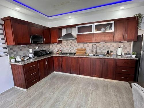 a large kitchen with wooden cabinets and appliances at La Vega City home with pool in Concepción de La Vega