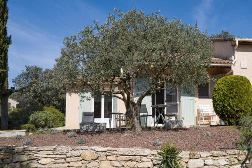 une maison avec un arbre devant dans l'établissement LES CISTES, à Lioux