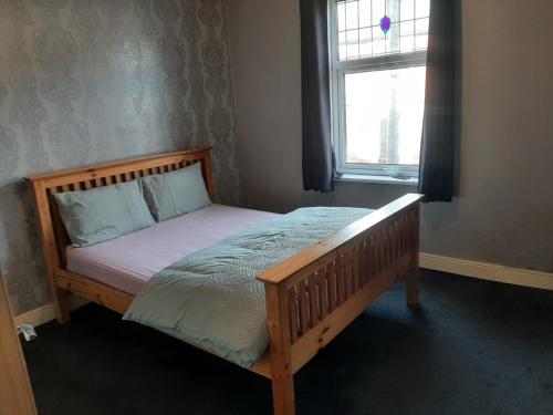 a wooden bed in a bedroom with a window at Nice 4 bedroom house in Nottingham