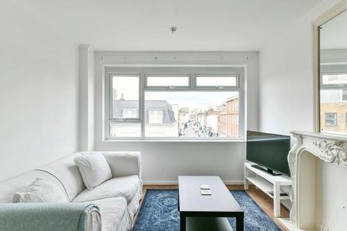 - un salon avec un canapé et une fenêtre dans l'établissement The Elden - No 9 - Fairway Hosting, à Londres