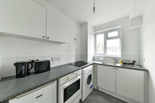 - une cuisine blanche avec un évier et un lave-vaisselle dans l'établissement The Elden - No 9 - Fairway Hosting, à Londres