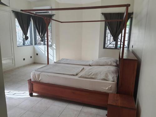 ein Schlafzimmer mit einem Himmelbett in einem Zimmer mit Fenstern in der Unterkunft Appartement Seth in Lomé