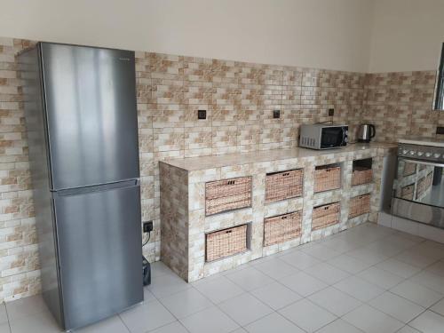 a kitchen with a stainless steel refrigerator and brick walls at Appartement Seth in Lomé