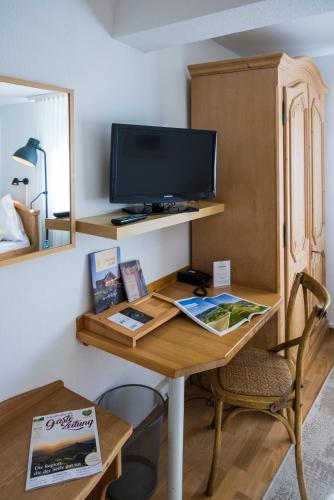 a room with a desk with a television and a chair at Widmann's Löwen in Königsbronn