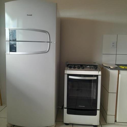 a kitchen with a stove and a refrigerator at Apartamento inteiro e climatizado in Ipatinga