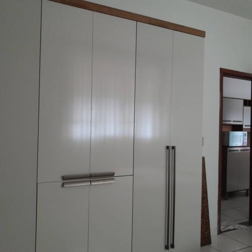 伊帕廷加的住宿－Apartamento inteiro e climatizado，厨房里设有一扇带门的白色橱柜