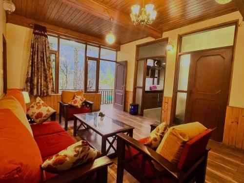 4 Bedroom Luxury Bungalow in Manali with Beautiful Scenic Mountain & Orchard View في مانالي: غرفة معيشة مع أريكة وطاولة