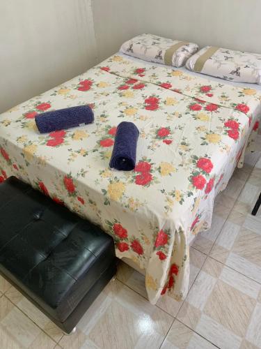 a bed with a flowered blanket with a hat on it at Quarto confortável perto de tudo 03 in Belém