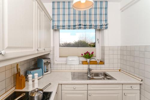 eine Küche mit einem Waschbecken und einem Fenster in der Unterkunft Haus Dorfglück in Morsum