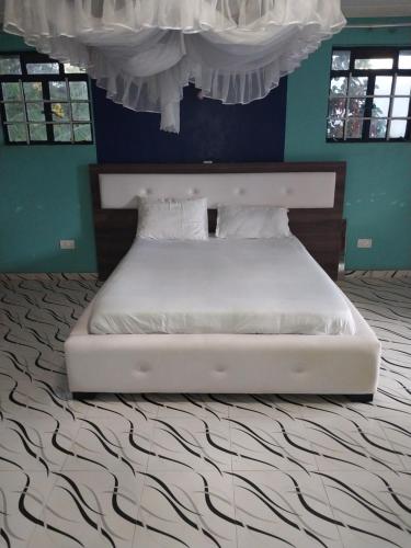 uma cama branca num quarto com uma parede azul em Radisson Villa em Kisumu