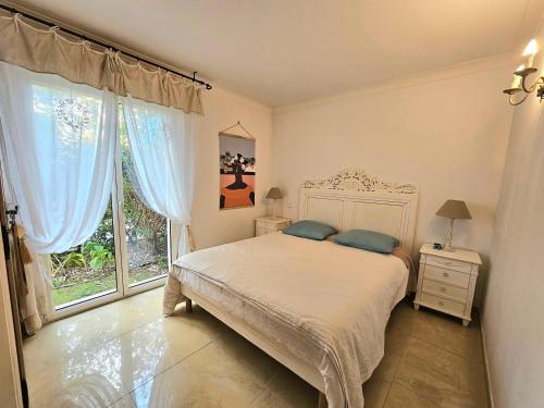 une chambre avec un lit et une grande fenêtre dans l'établissement T4 3chambres, jardin, piscine chauffée proche de la mer, à Antibes