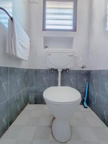a white toilet in a bathroom with a window at Sunshine Villa & Homestay in Tiruchirappalli