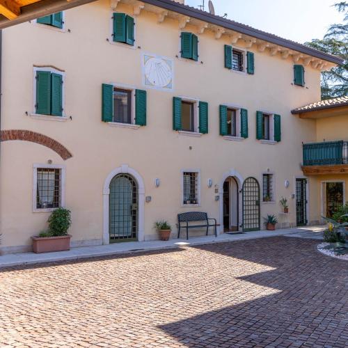 a large white building with green shutters and a courtyard at A Casa di Tom in SantʼAmbrogio di Valpolicella