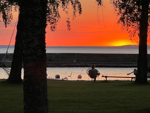 a person sitting on a bench watching the sunset at Borghamn Strand in Borghamn