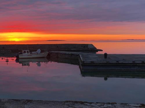 a boat is docked at a dock at sunset at Borghamn Strand in Borghamn